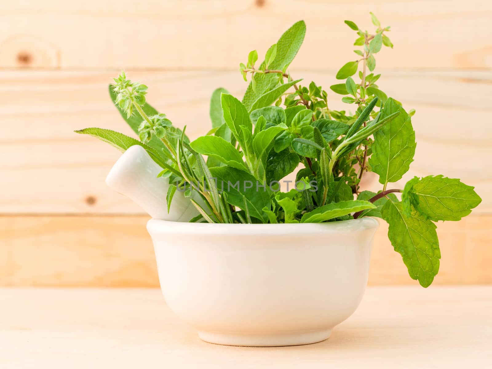 Alternative health care fresh herbal in white mortar on wooden background.