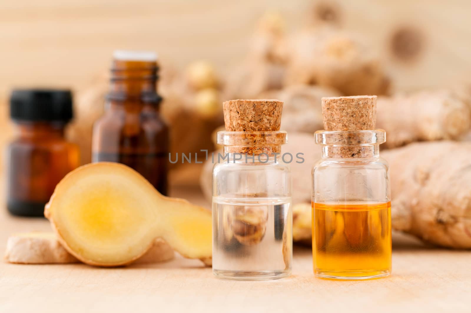 Bottles of ginger oil and ginger on wooden background with selective focus.