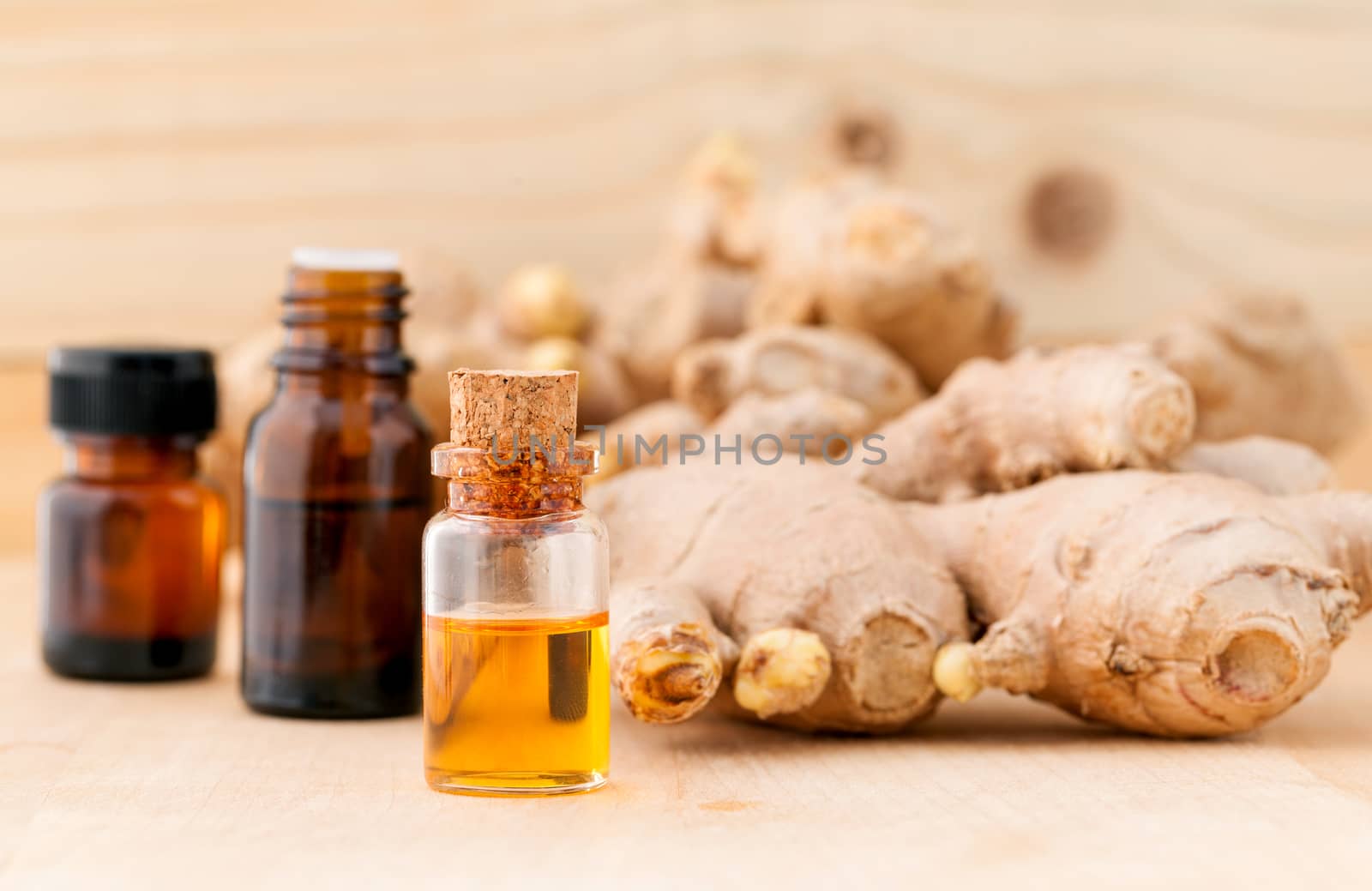 Bottles of ginger oil and ginger on wooden background with selec by kerdkanno