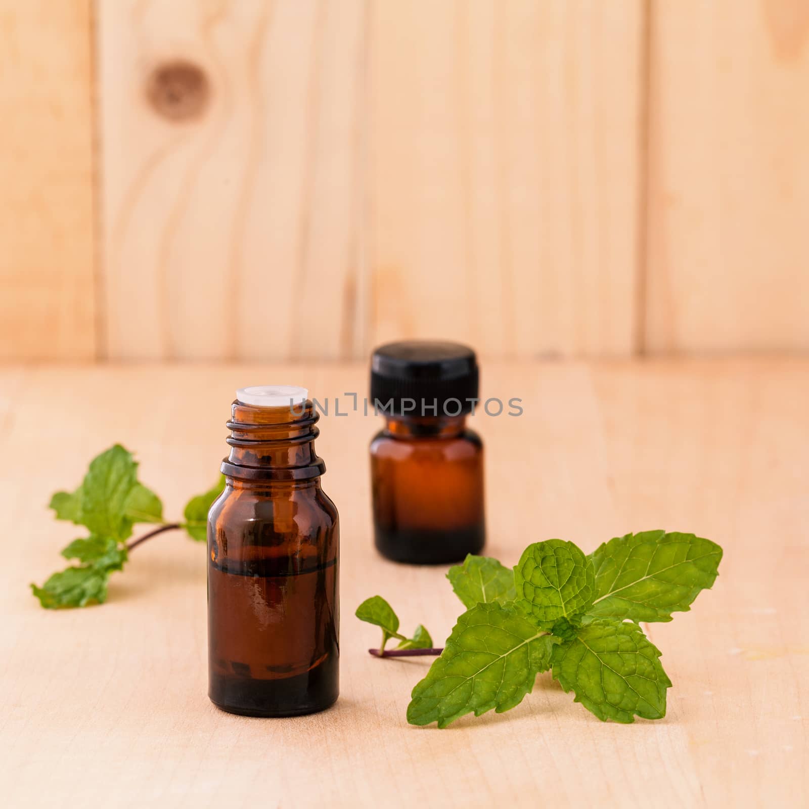 Bottle of mint essential oil on wooden background with selective by kerdkanno