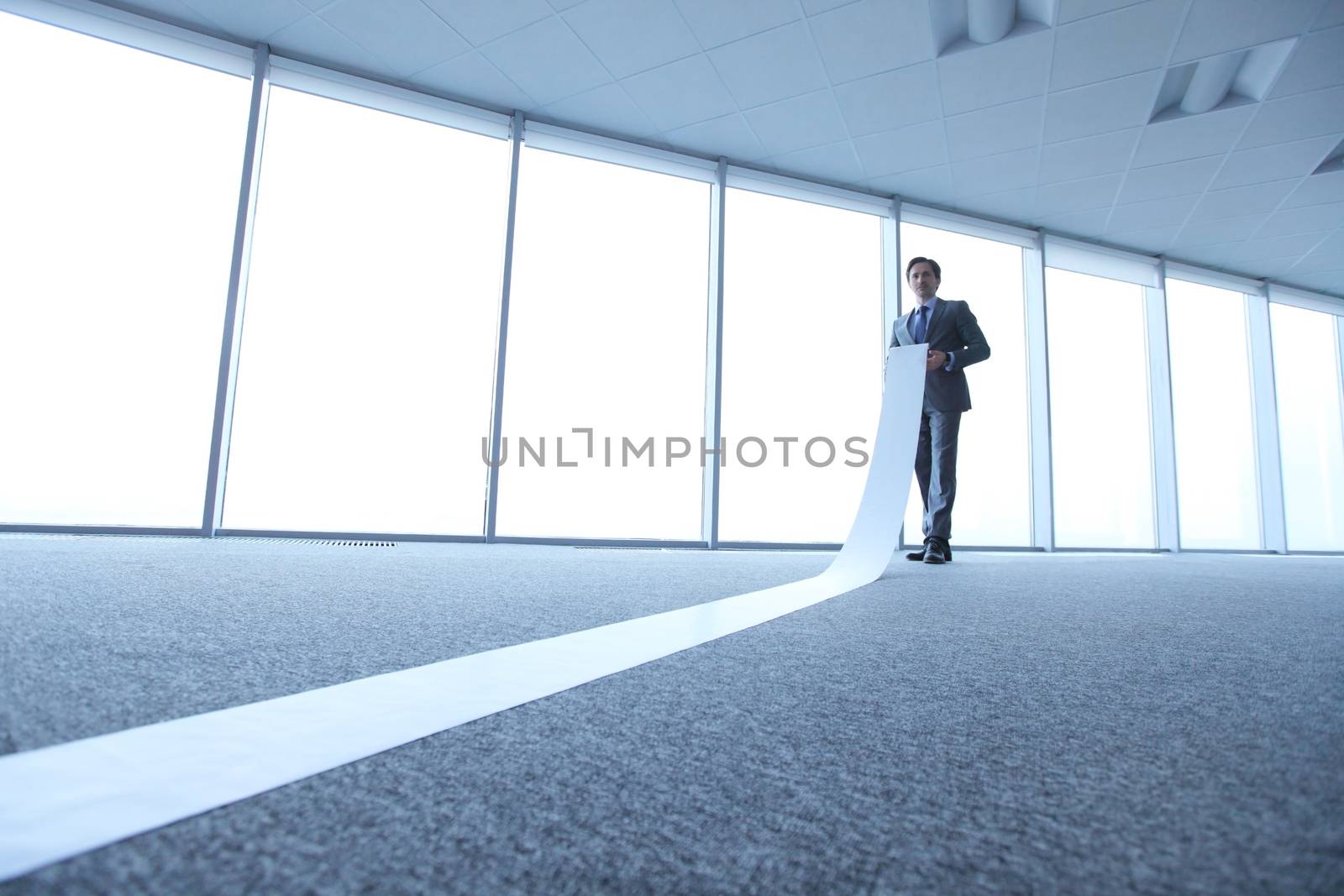 Office worker unrolling long sheet of paper