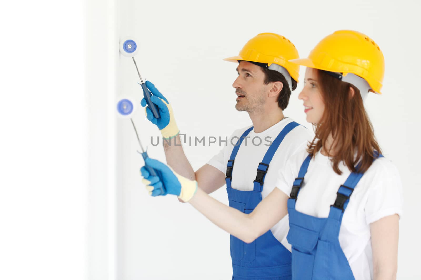 two workmen painting white wall