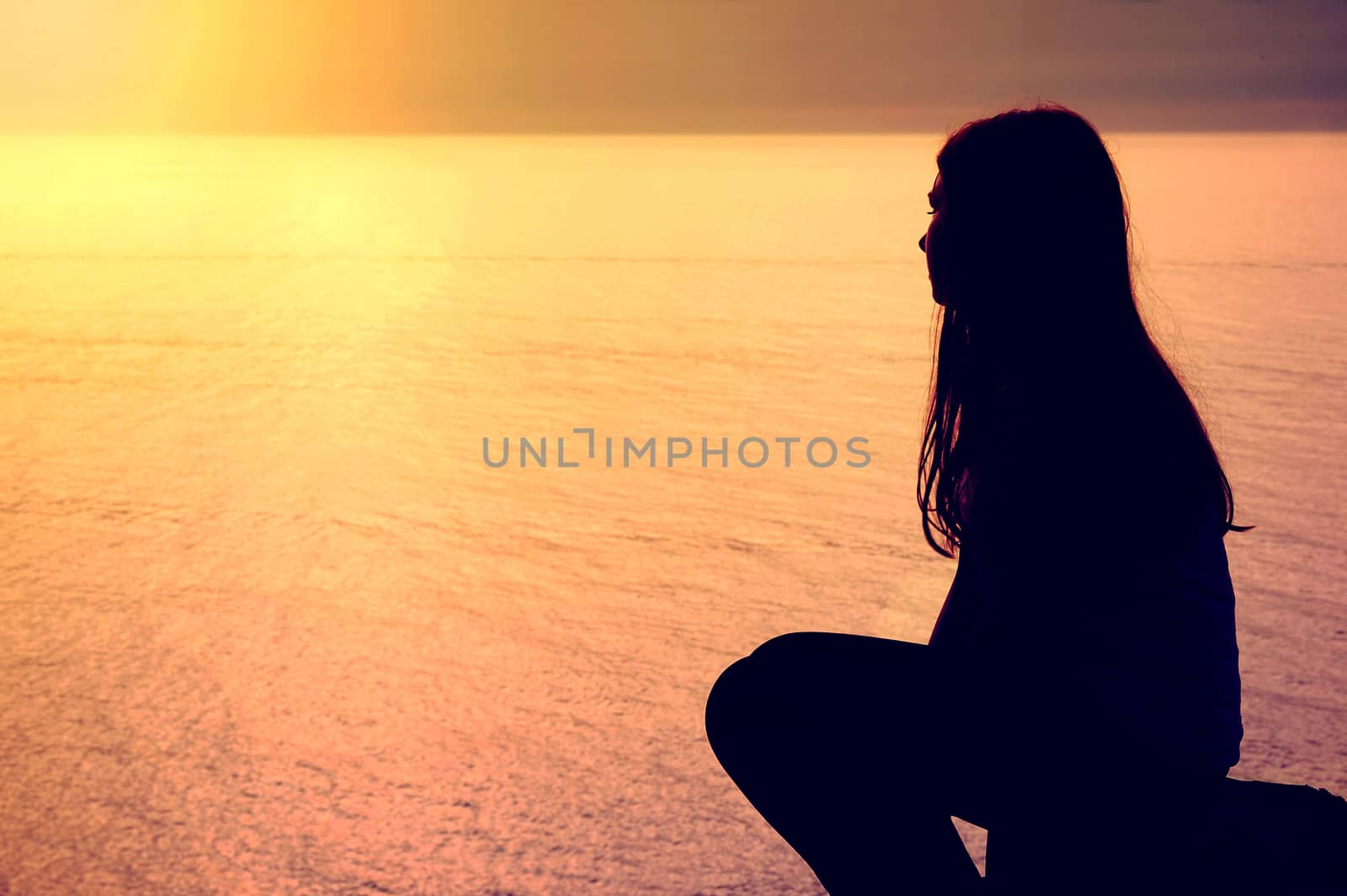 Emotion conceptual image. Lonely young woman on the beach, sitting near ocean.