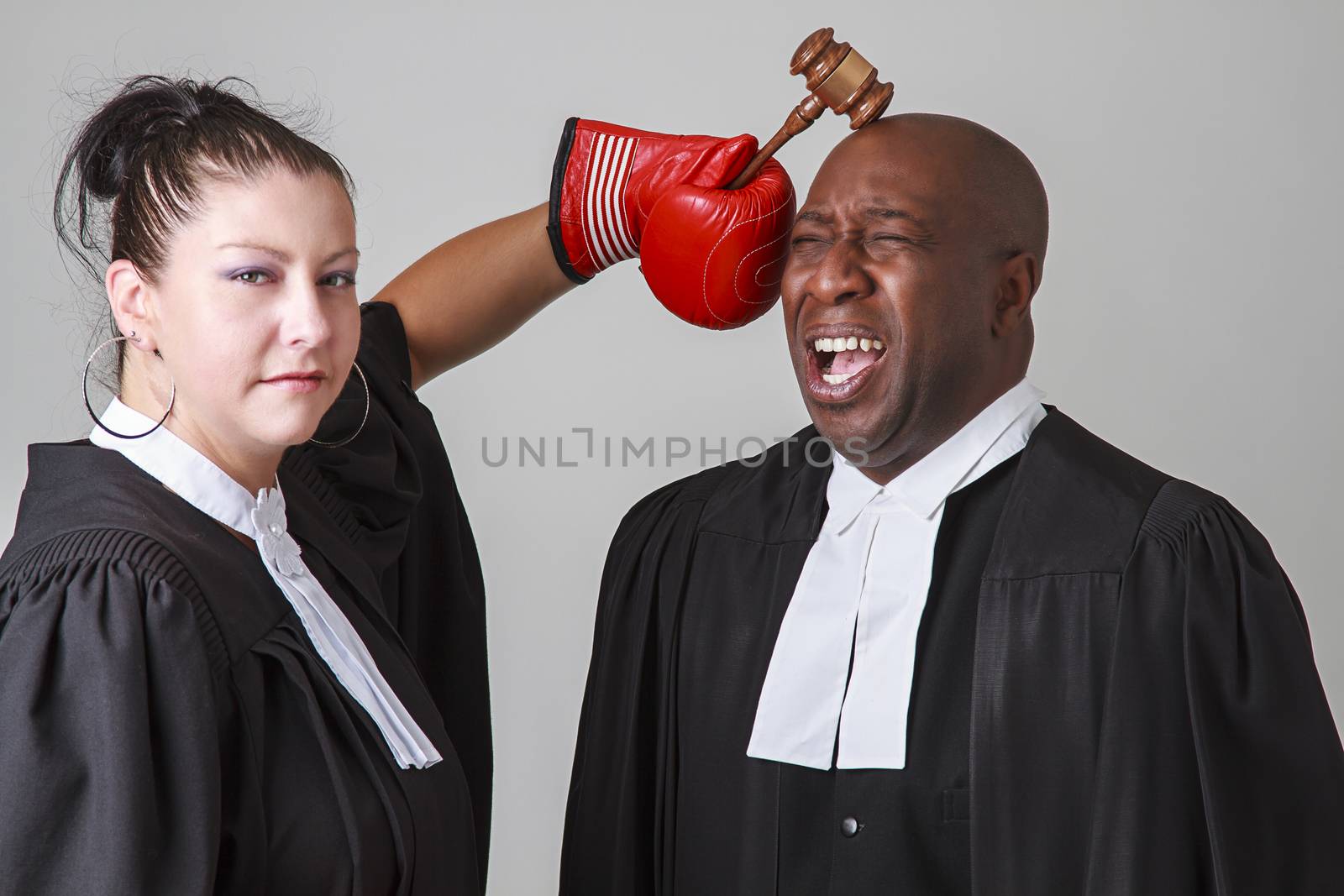 woman hammering a man on the head with a gavel, both wearing canadian lawyers toga