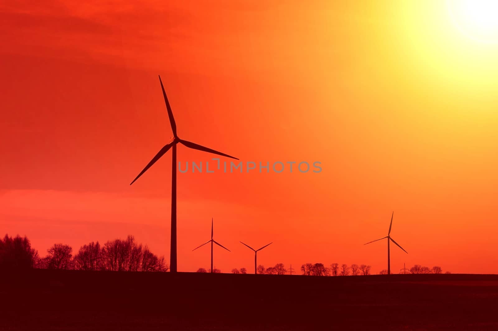 Hot sun and red sky over windmills. Alternative energy concept.