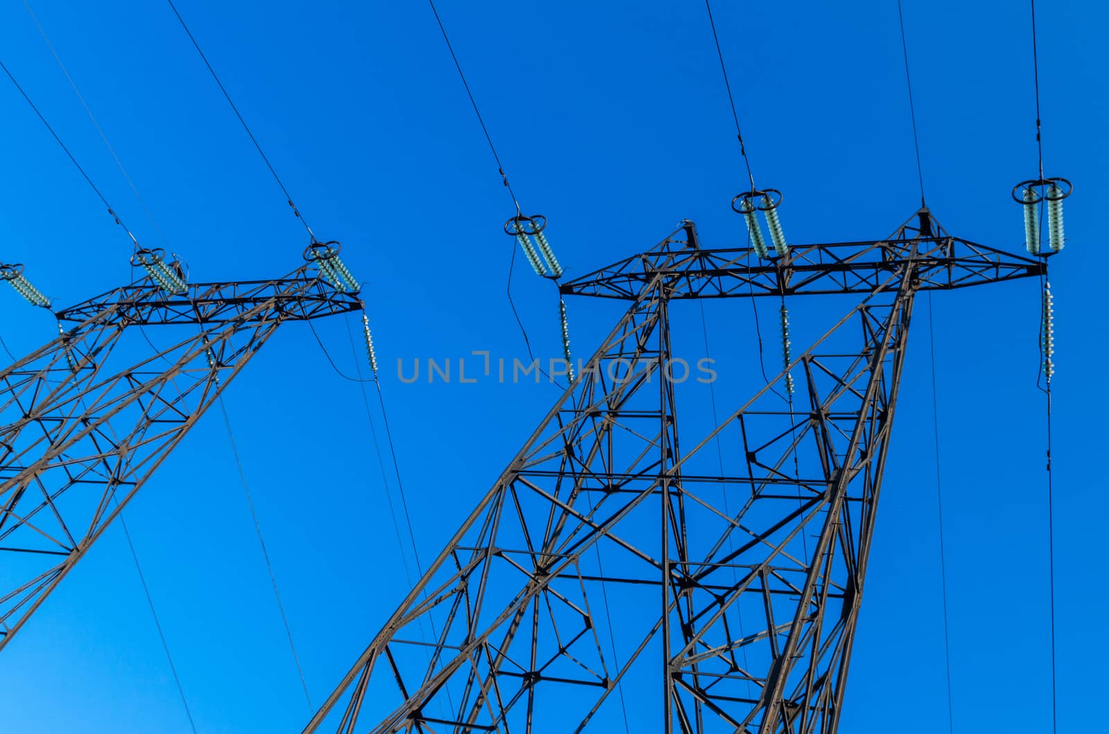 supports of high-voltage power lines against the blue sky