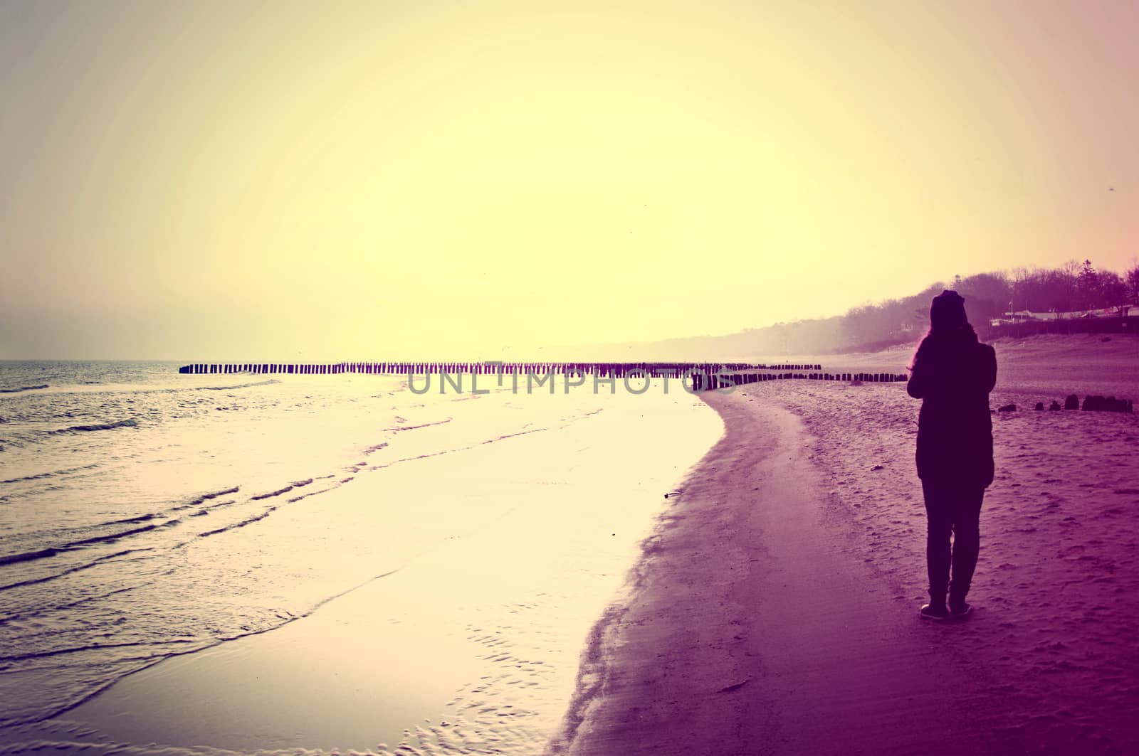 Emotion conceptual image. Lonely woman walking on the beach. Instagram vintage picture.