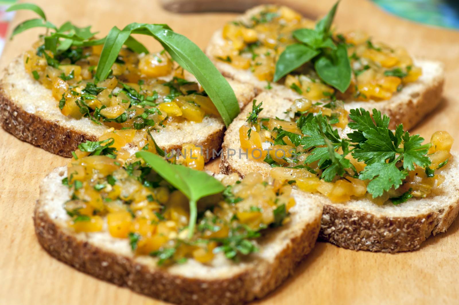 Italian bruschetta topped with yellow tomatoes, parsley, basil and rucola