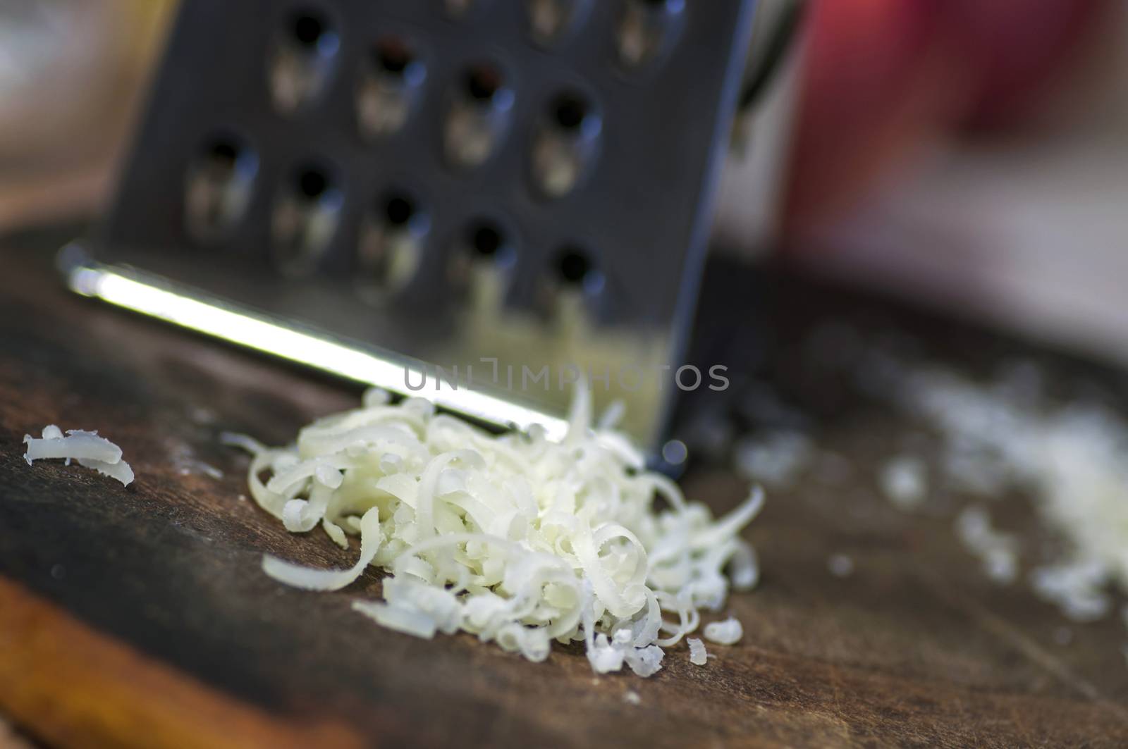 Grated cheese and grater on cutting board close up