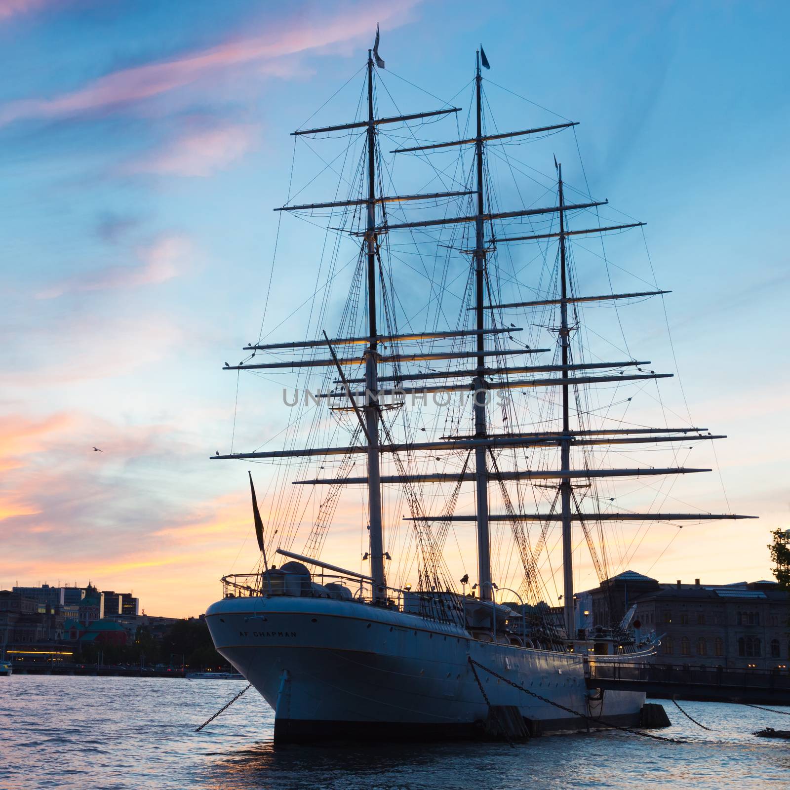 Panoramic view of swedish capital Stockholm in sunset. Silhouette of large traditional wooden sailboat and old medieval downtown of Gamla stan in the background. Copy space. Square composition.