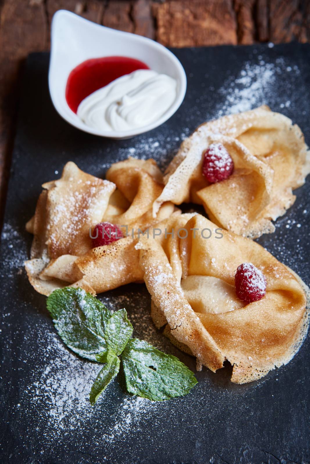 Crepes with raspberries with copy space on black background