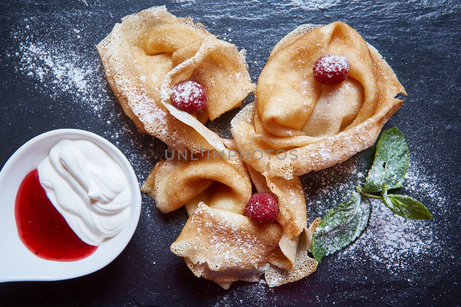 Crepes with raspberries with copy space on black background