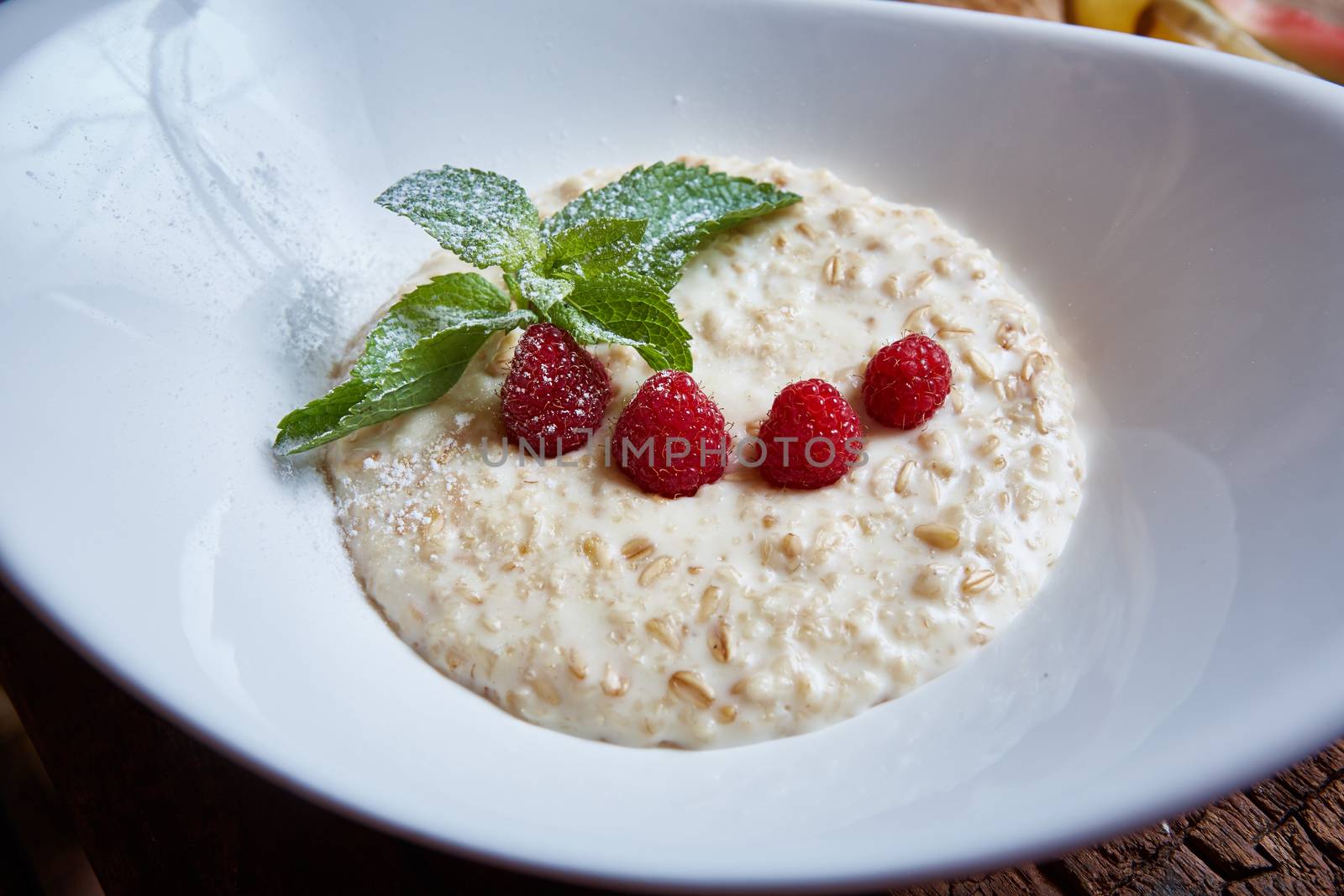 oatmeal with raspberries and mint in white plate
