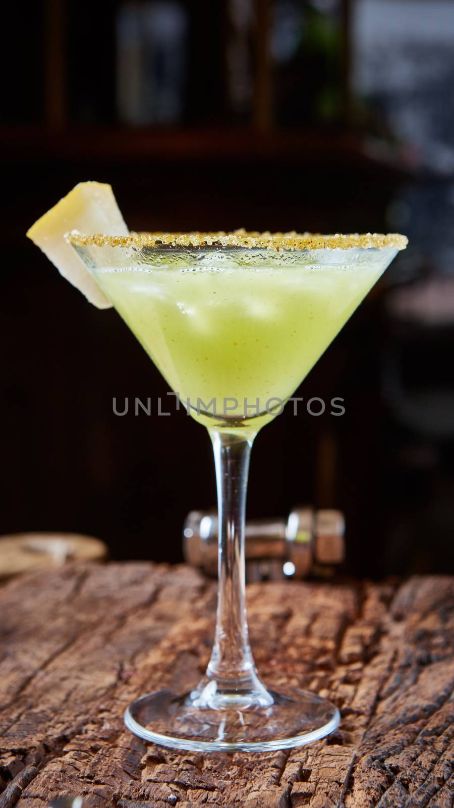 Green margarita melon cocktail with copy space on wooden background.