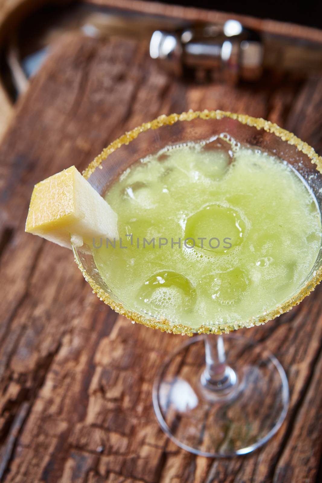 Green margarita melon cocktail with copy space on wooden background.