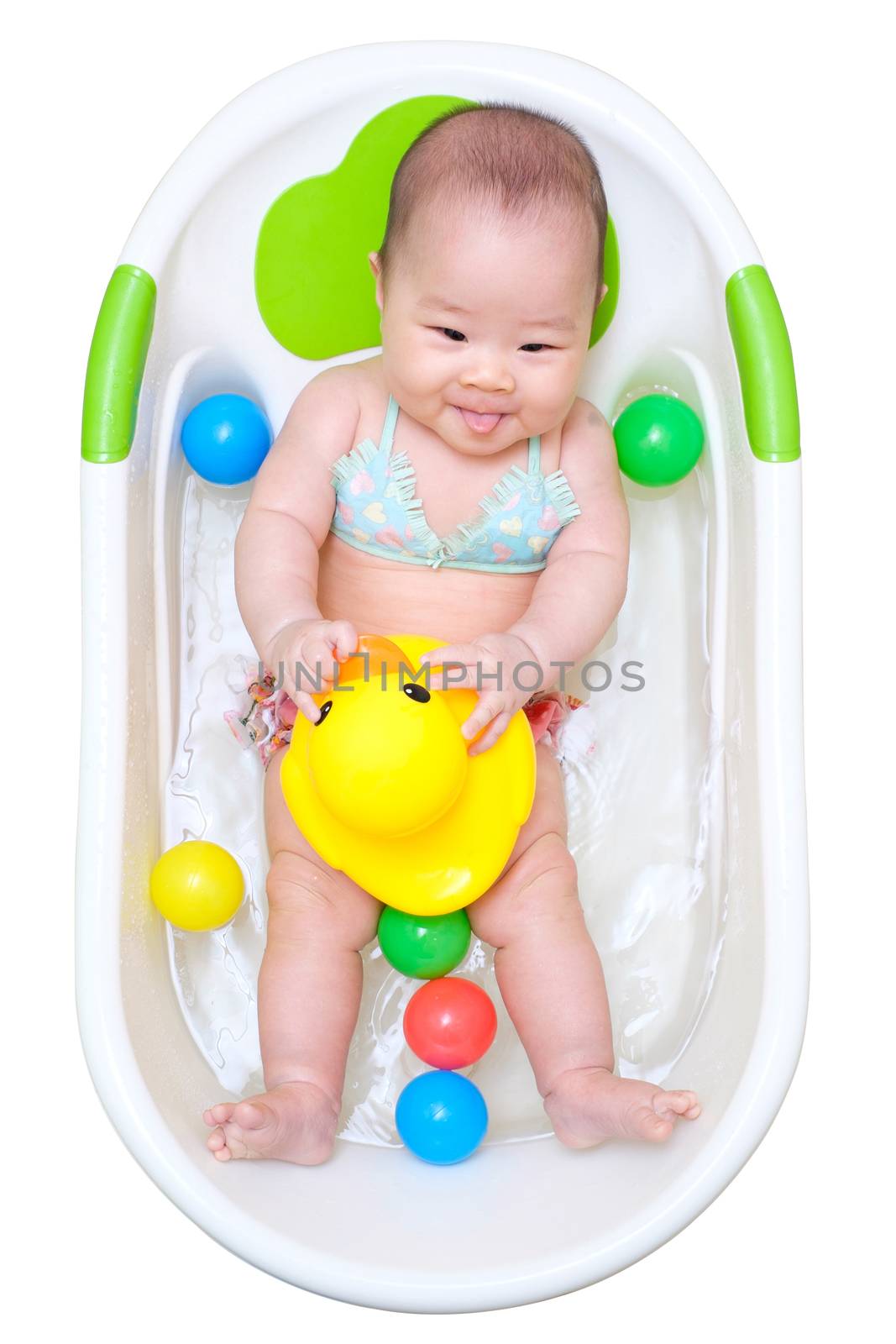 Asian baby girl taking a bath in white tub and playing duck and have different color of plastic balls.