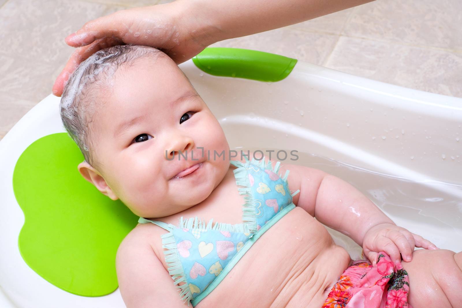 Mom washing baby girl hair, she put tongue out and smile