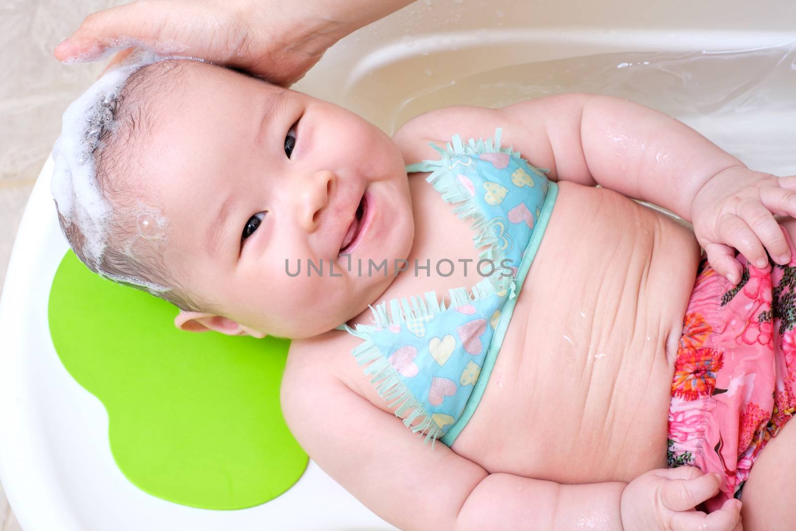 Mom washing baby girl hair. baby smiling and funny looking at the camera