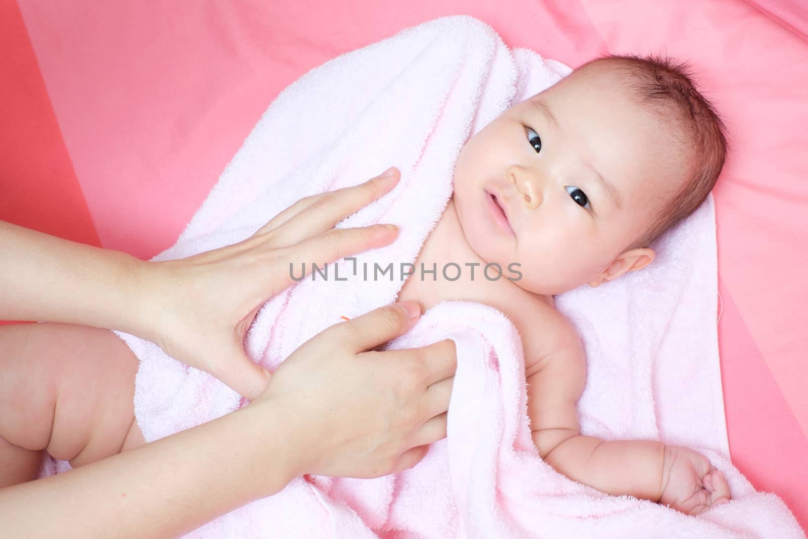 Mom rub her baby to dry whit pink towel