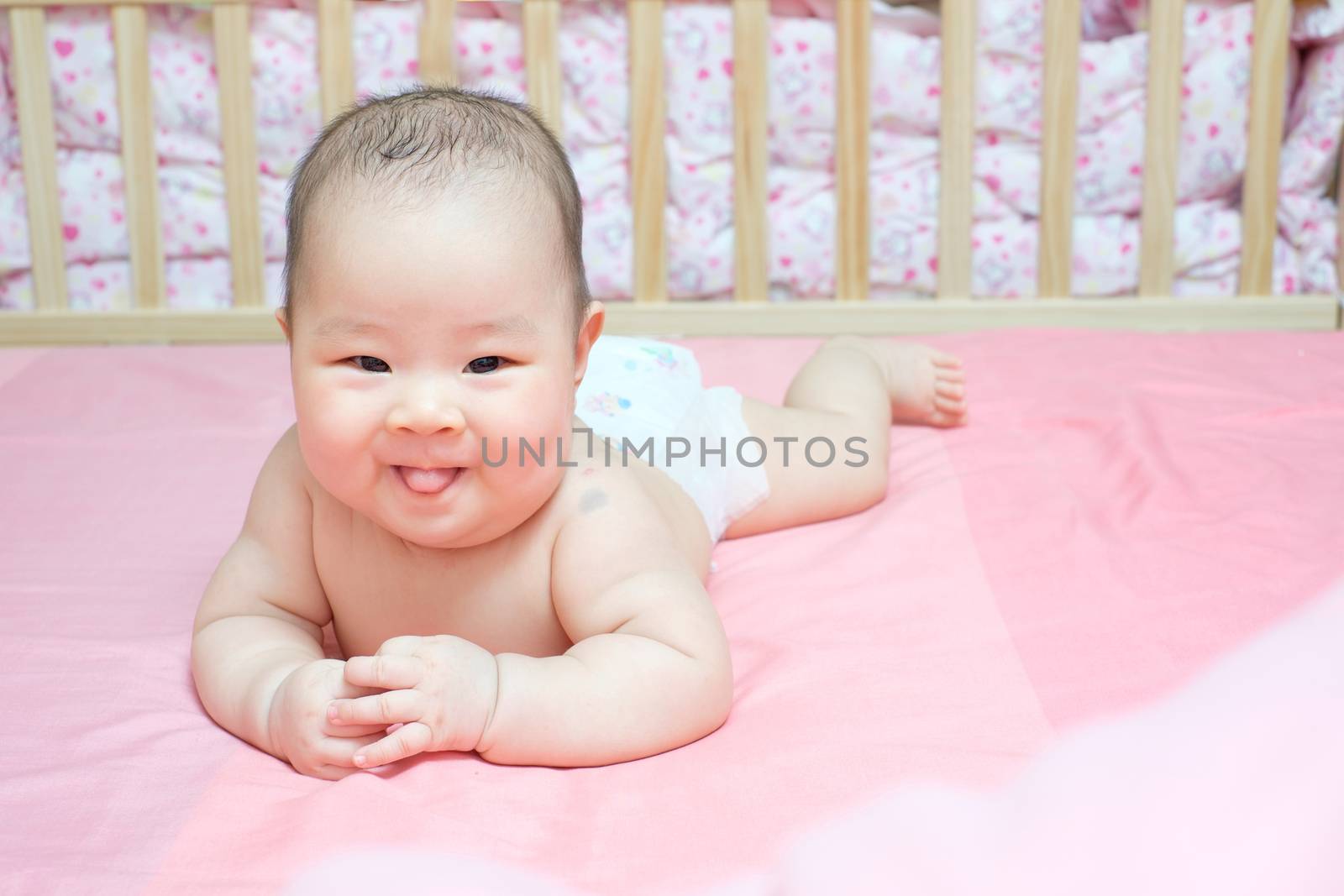 Asian baby girl scowl on pink bed