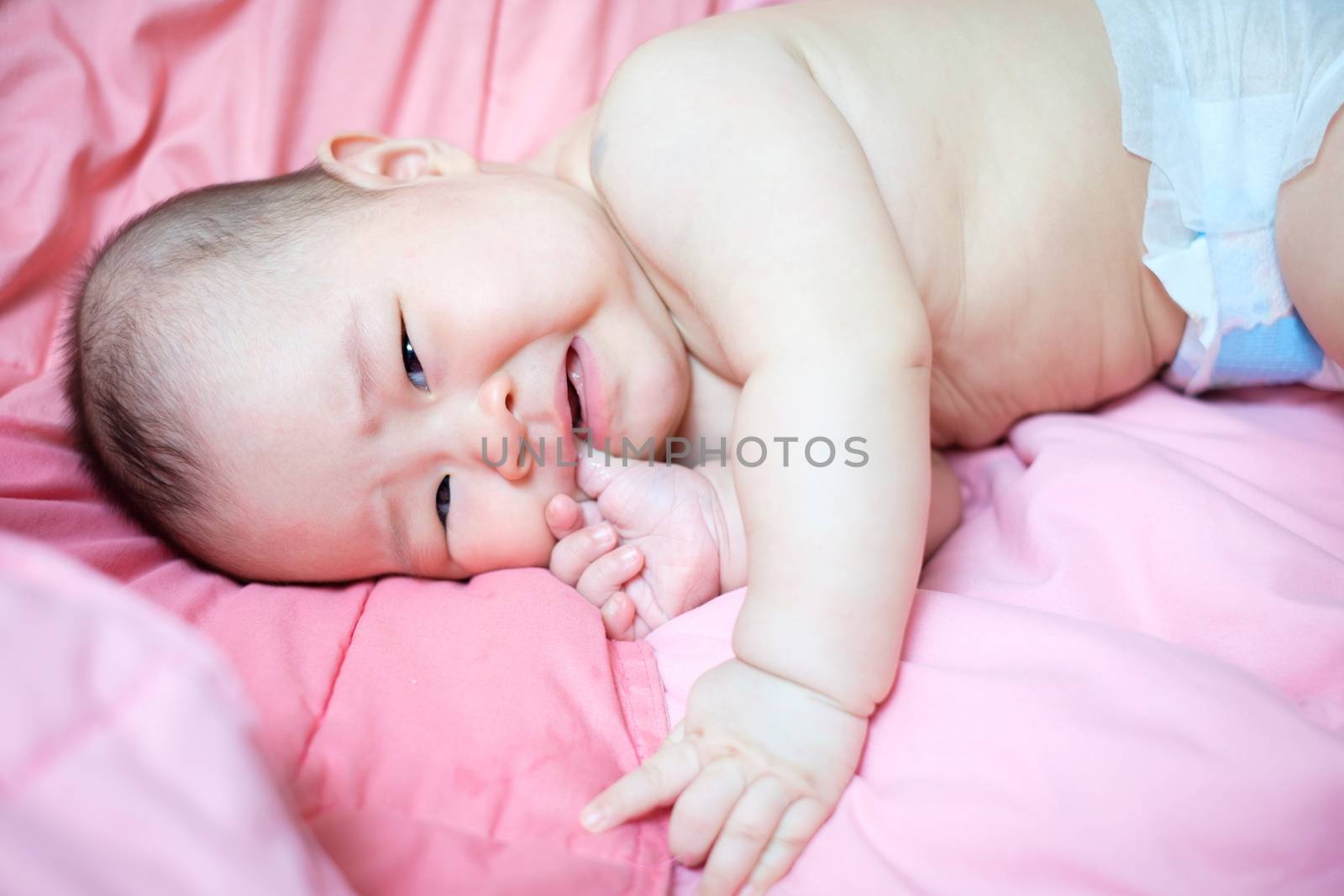 Asian baby girl crying on pink bed by zneb076