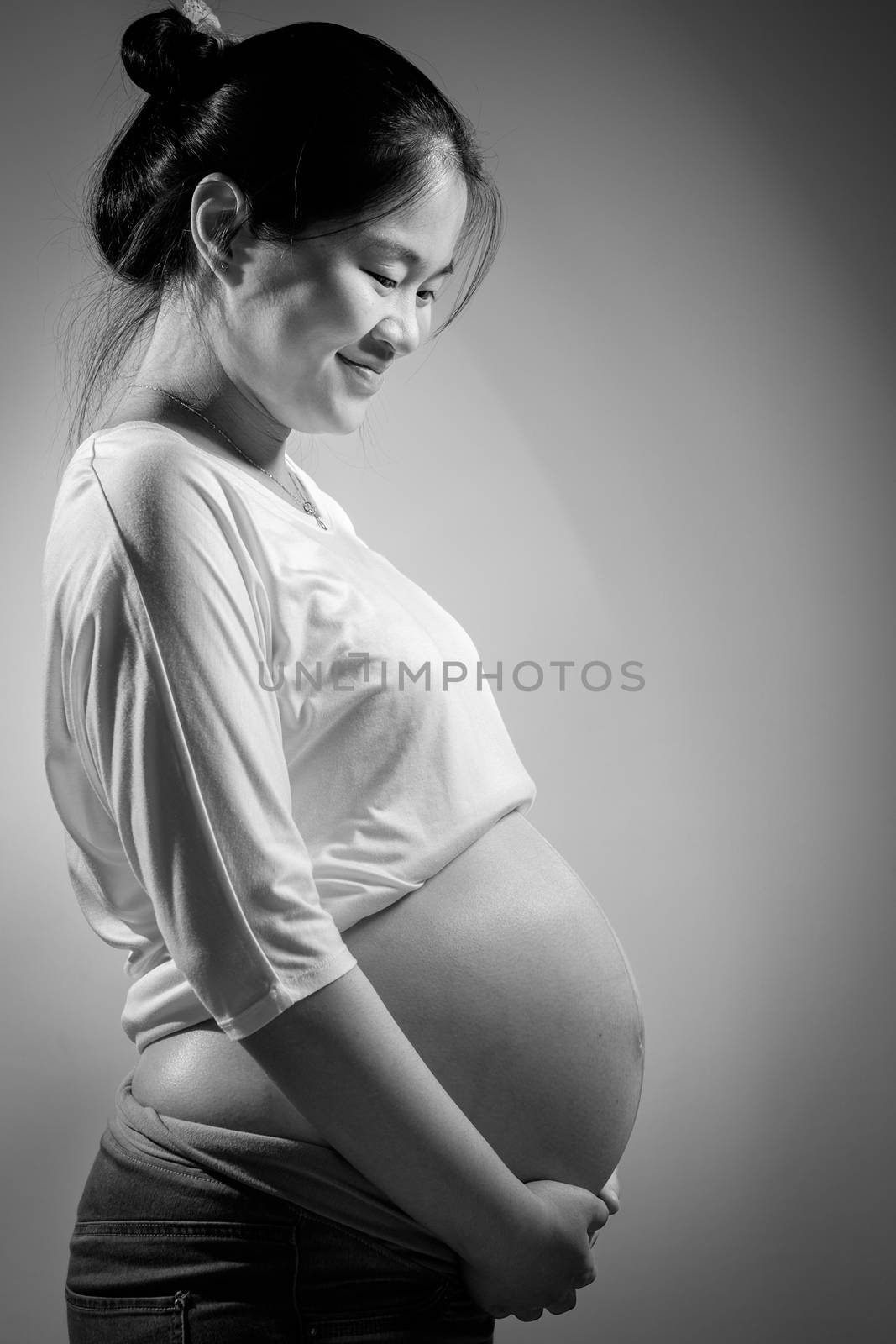 Asian pregnant woman in studio on white background and she holding her belly.
