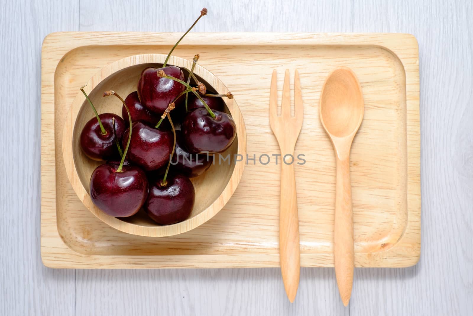cherry in wooden bowl and wooden plate