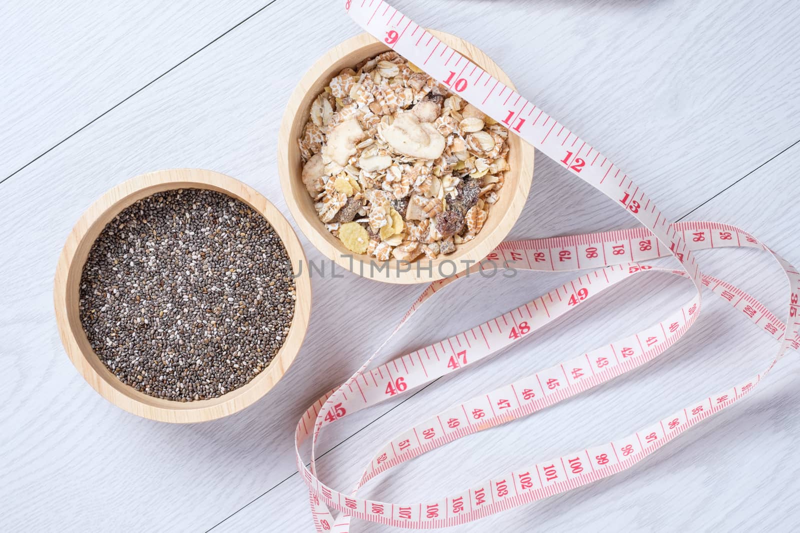 Muesli and chai seed in wooden bowl with tape measure