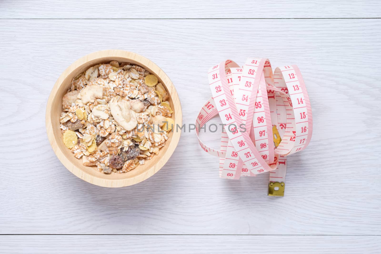 Muesli and tap measure on white wooden table