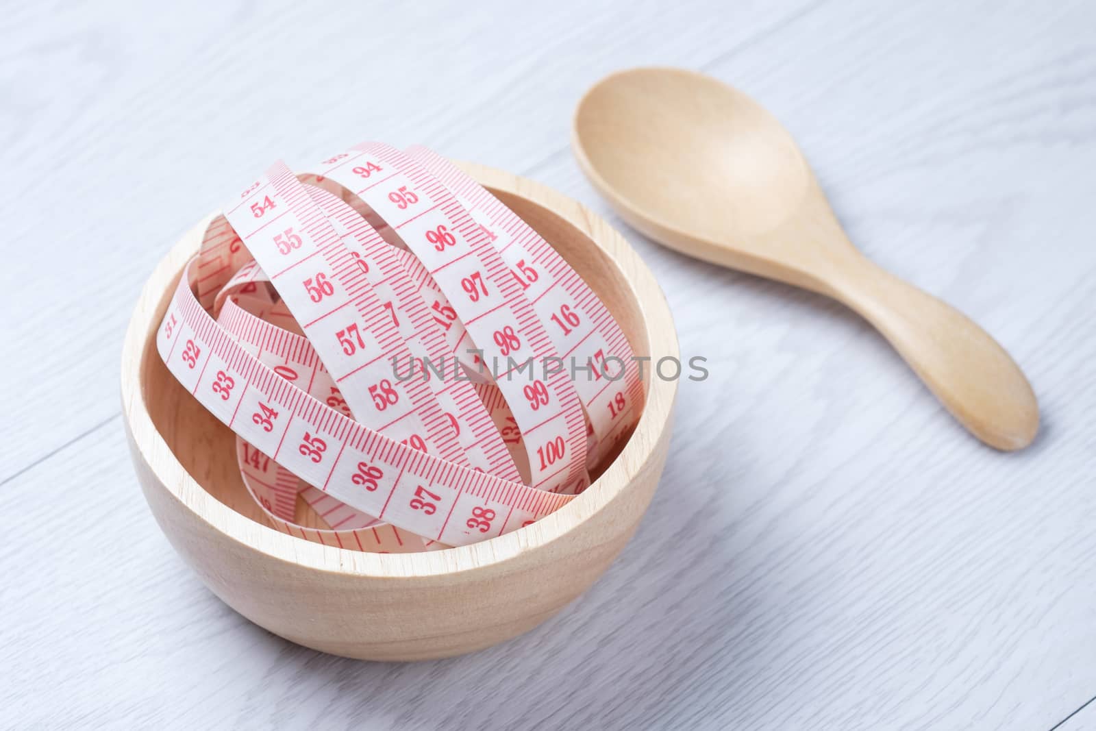 Tape Measure in wooden bowl on the white wooden floor. for someone who want to diet , weight loss