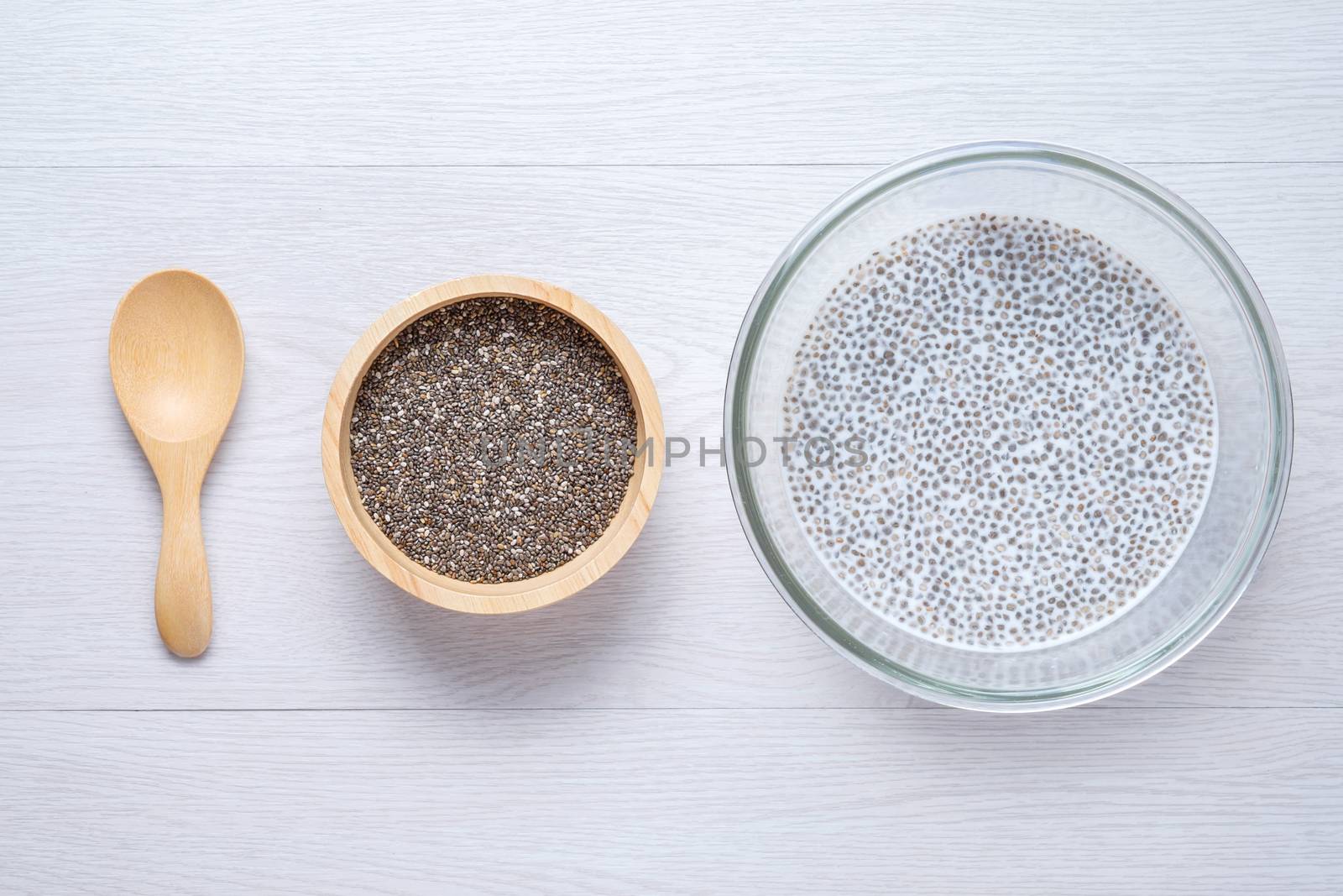 chai seed with milk in grass bowl and raw seed in wooden bowl put next to wooden spoon