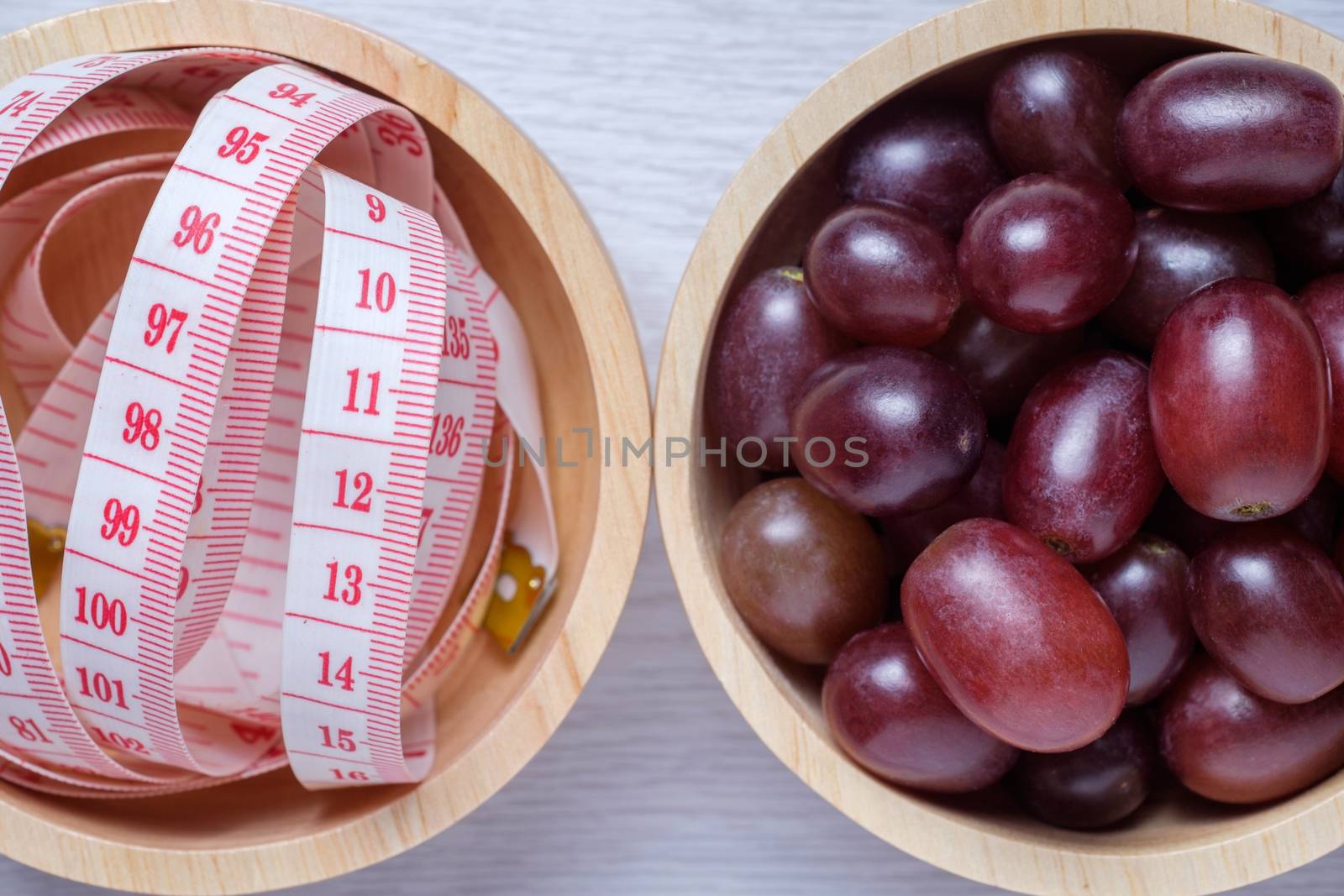 Red grapes and tape measure in wooden bowl. by zneb076