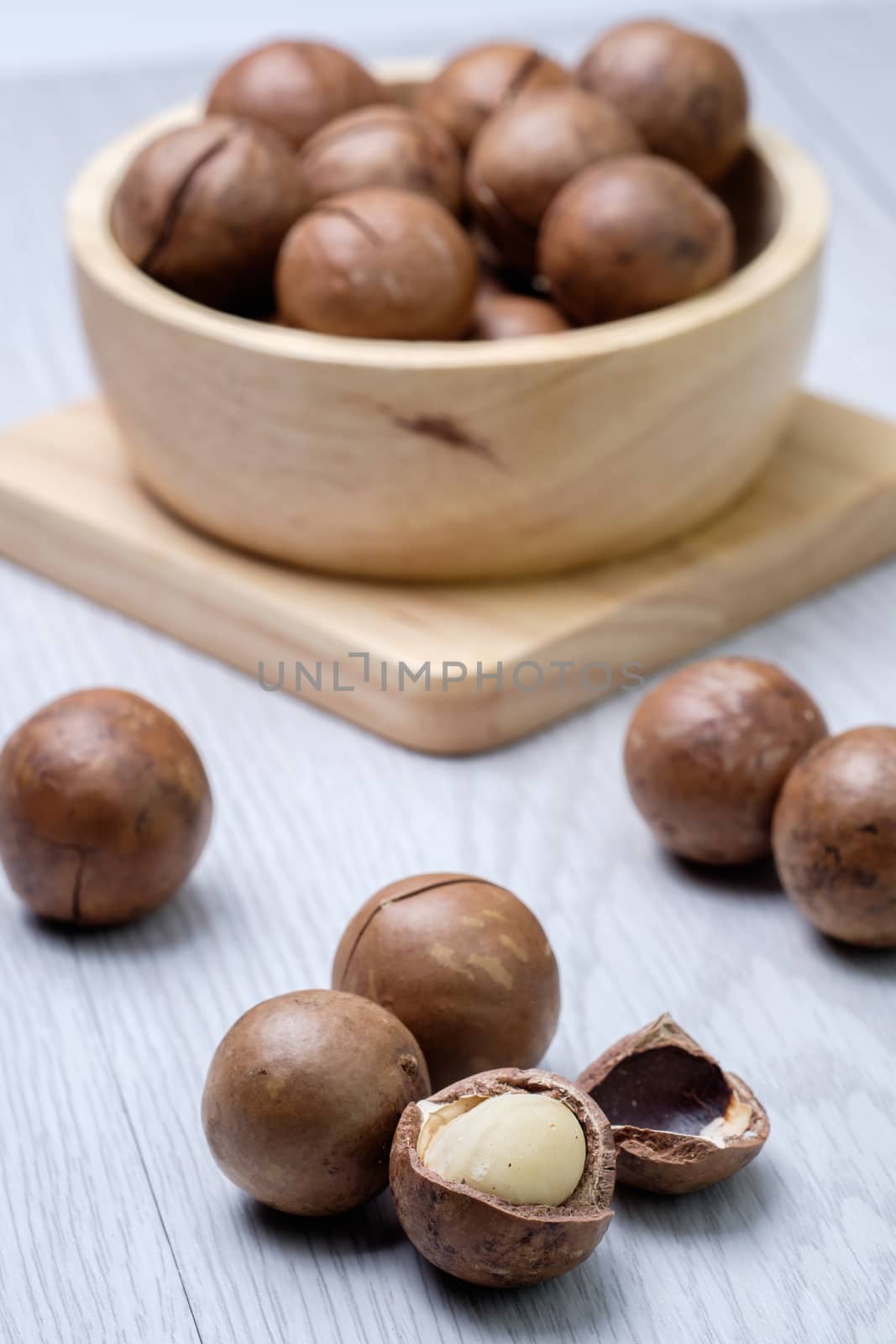 Macadamia in wooden bowl on white wooden table