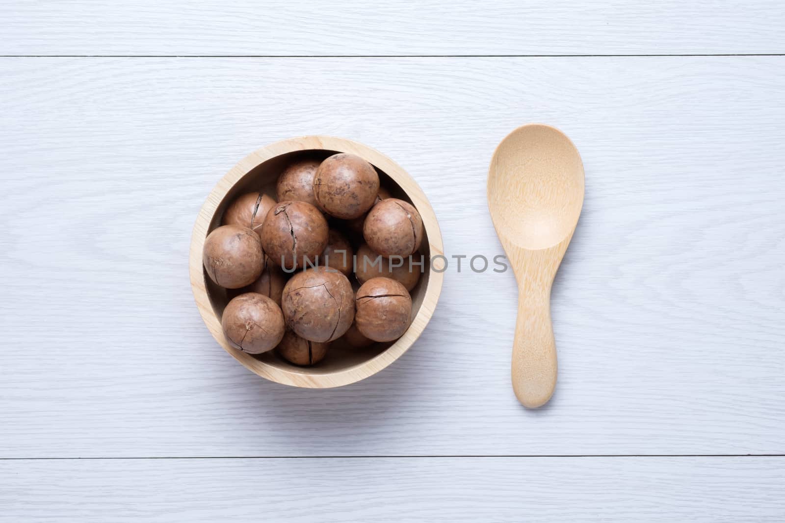 Top view macadamia in wooden bowl  on white wooden table by zneb076