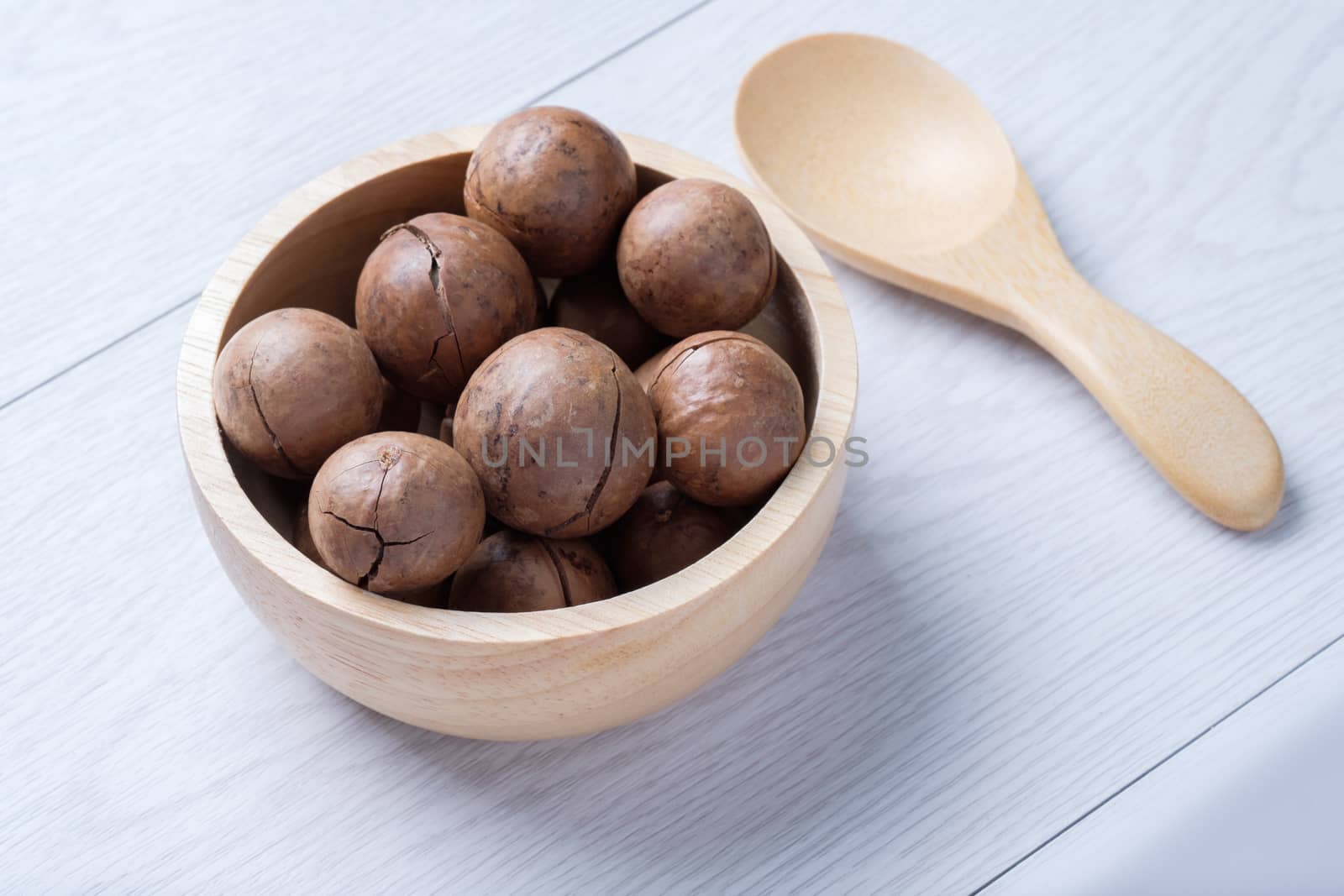 Macadamia in wooden bowl  on white wooden table by zneb076