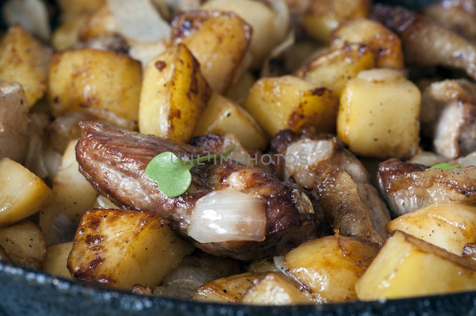 Potatoes fried on pan with meat close up