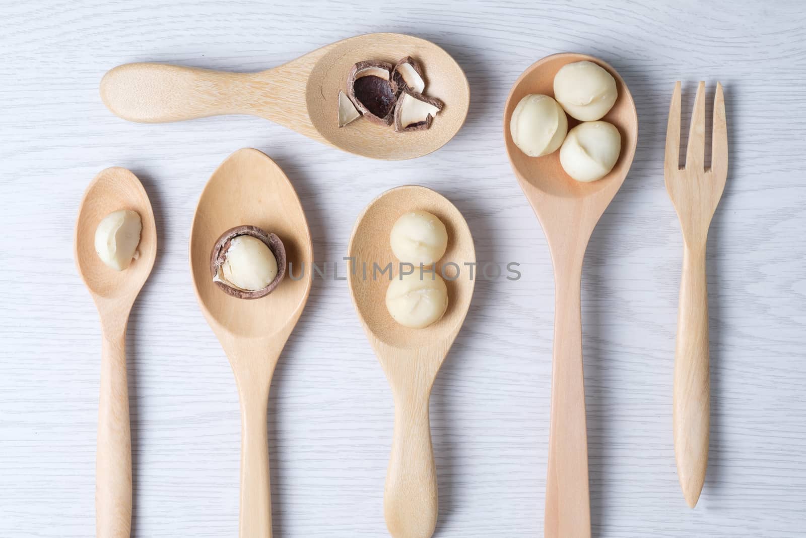 Top view macadamia nuts and shell in wooden spoons by zneb076