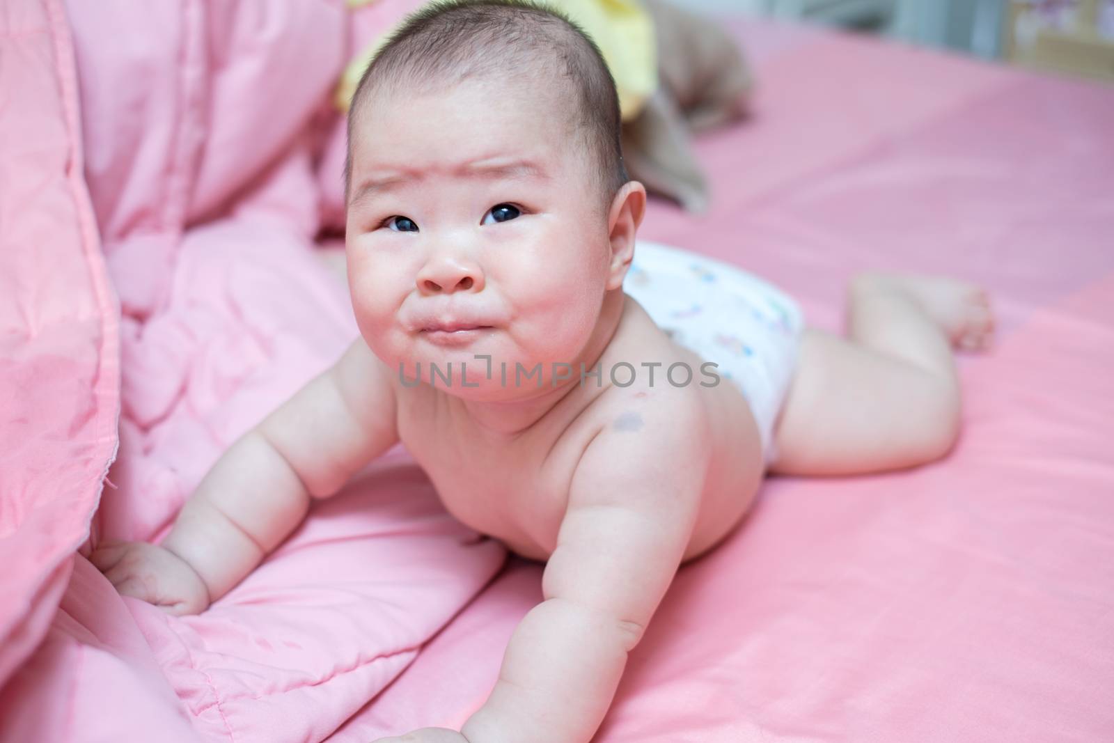 Asian baby girl crying on pink bed