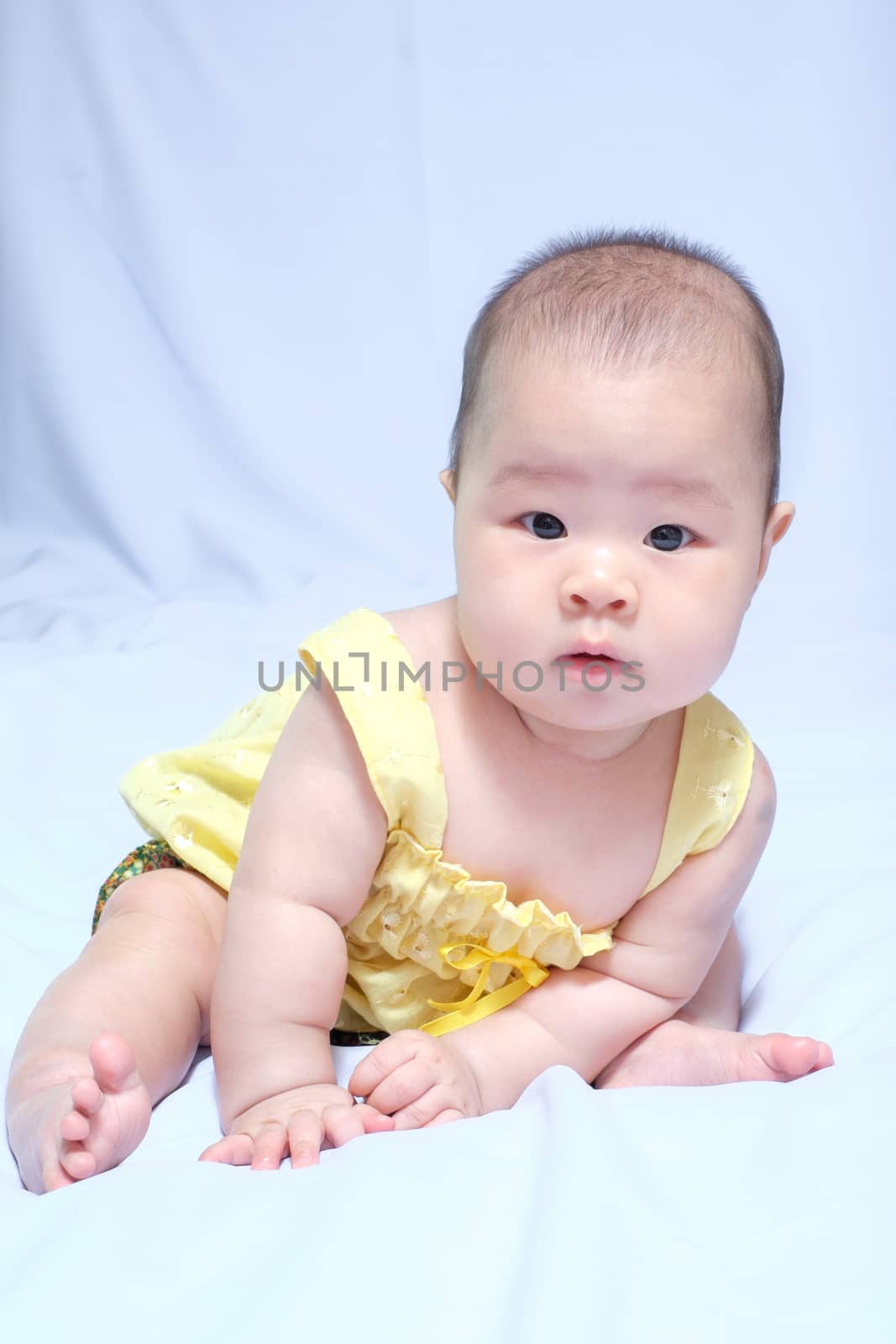 asian baby girl in traditional thai dress, she sit on the white bed, and looking at camera.
