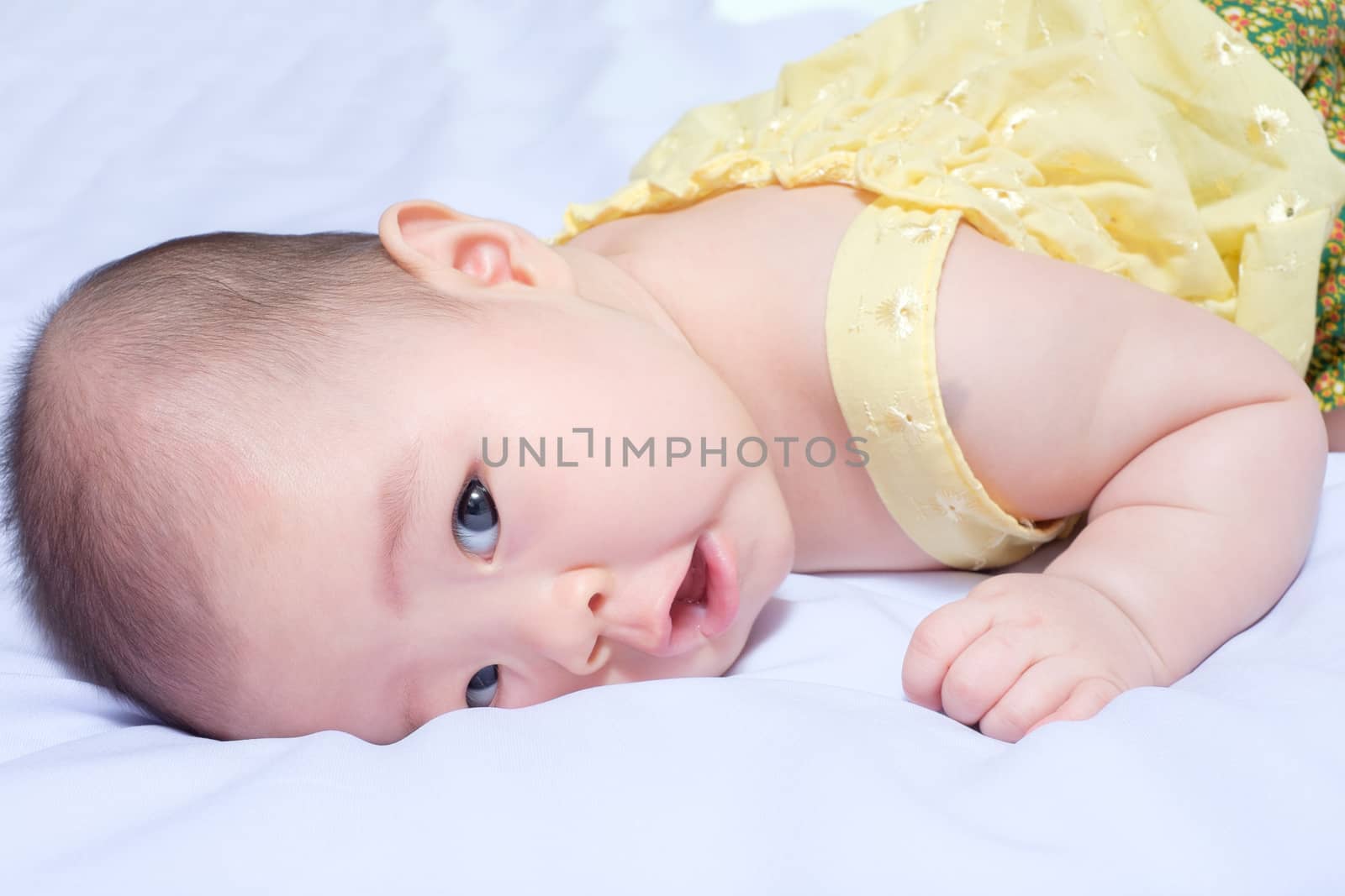 closeup asian baby girl in traditional thai dress, she lie prone, smile , open her mouth and looking at camera