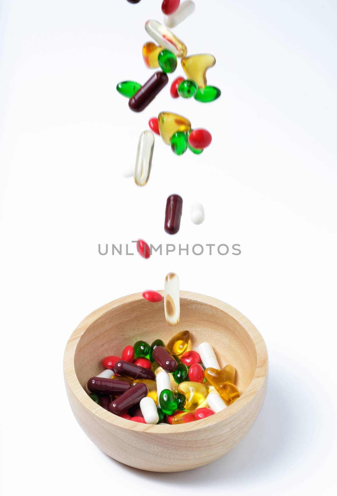 falling of colorful vitamin or medicine in to the wooden bowl