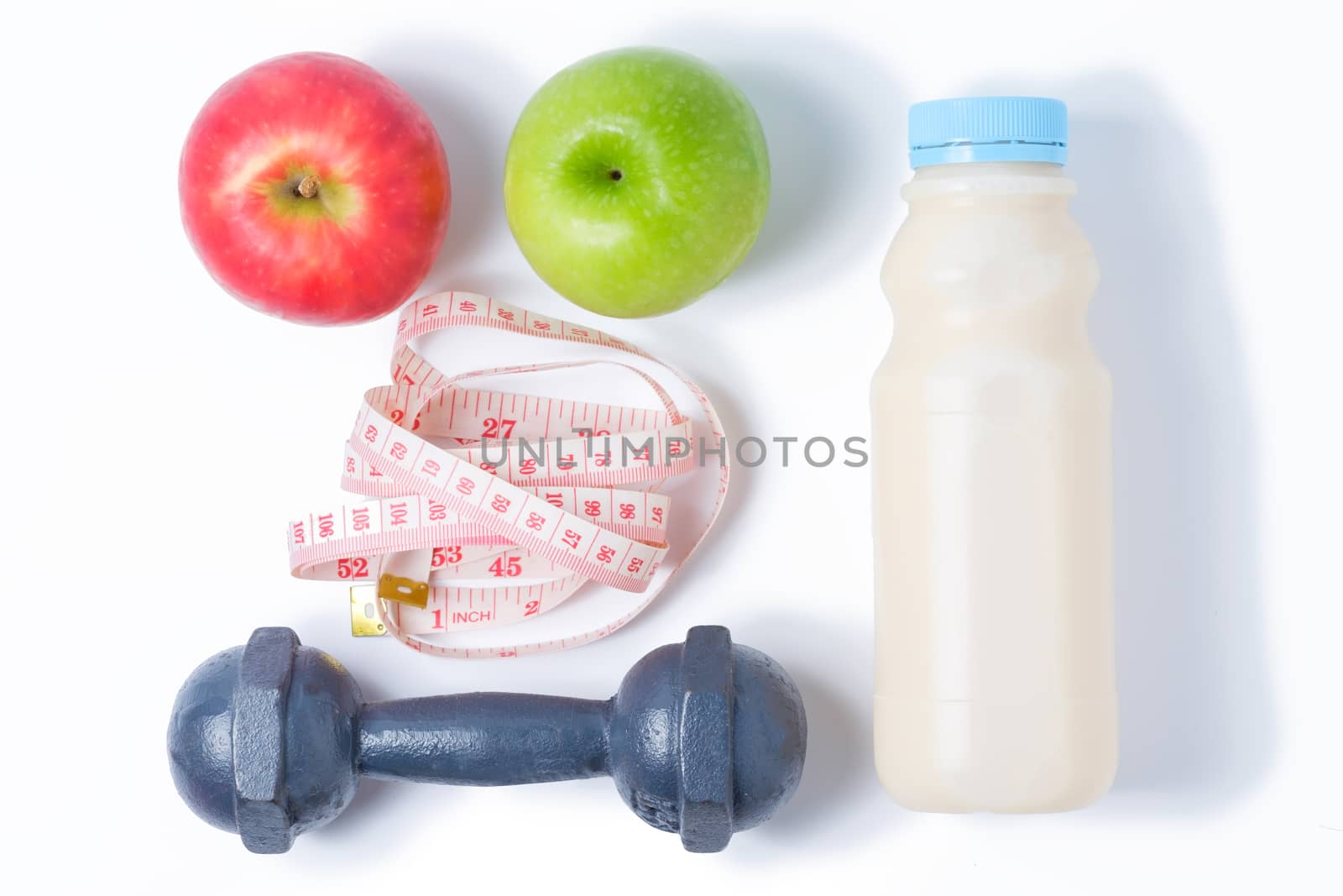 slice red , green apple with dumbbell, waist measure and milk on white background
