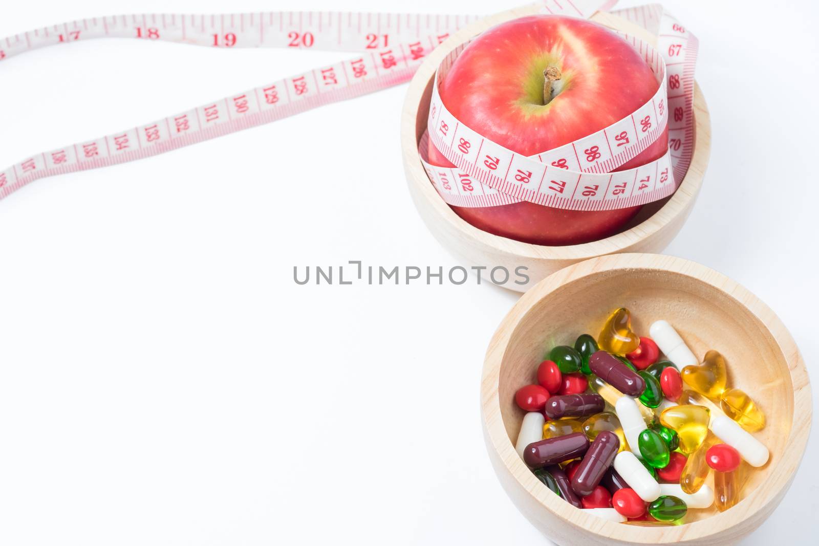 red apple and vitamin (medicine) in wooden bowl with waist measure on white background. space for adding your text.