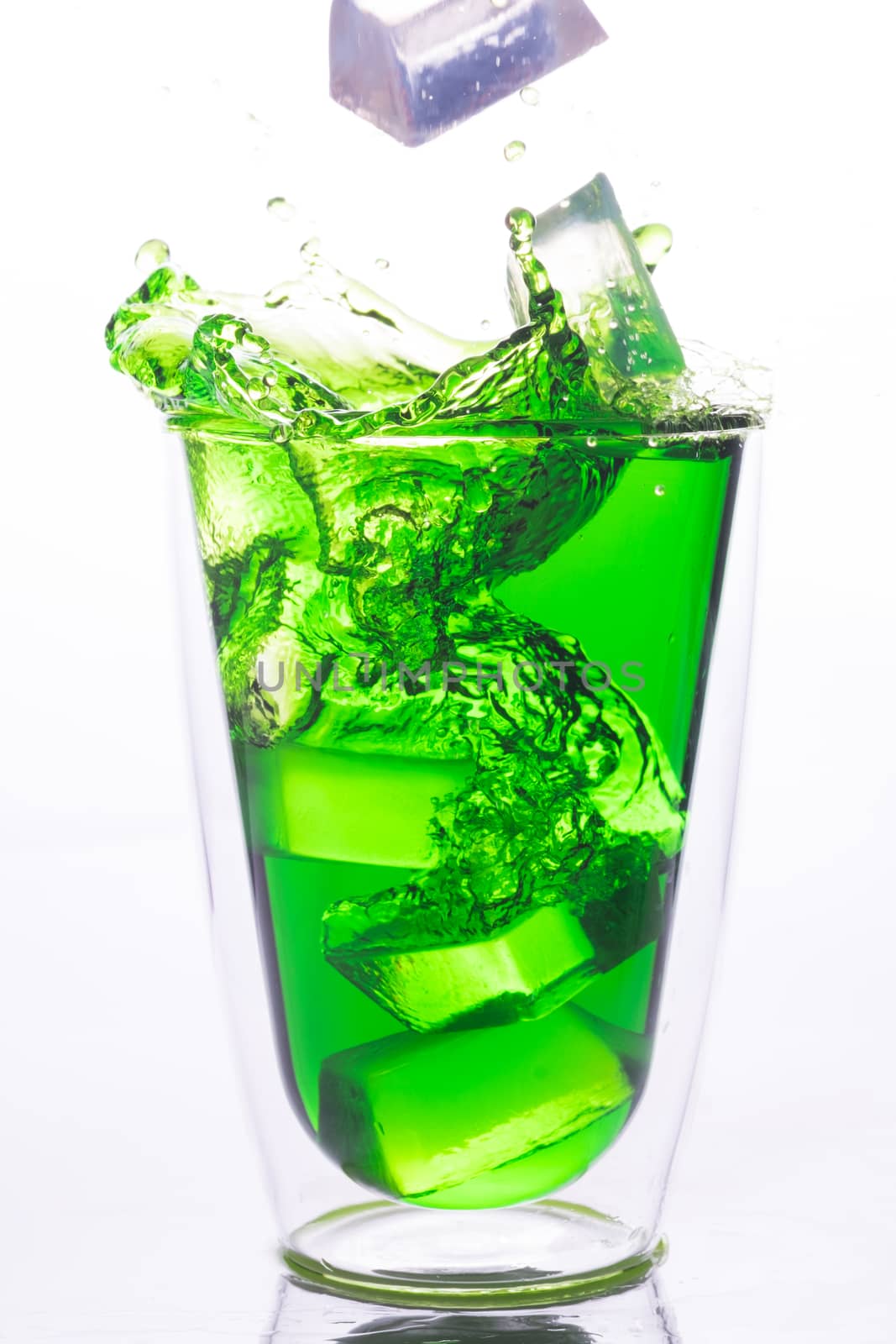 ice drop to glass of green water, green water splash out the glass