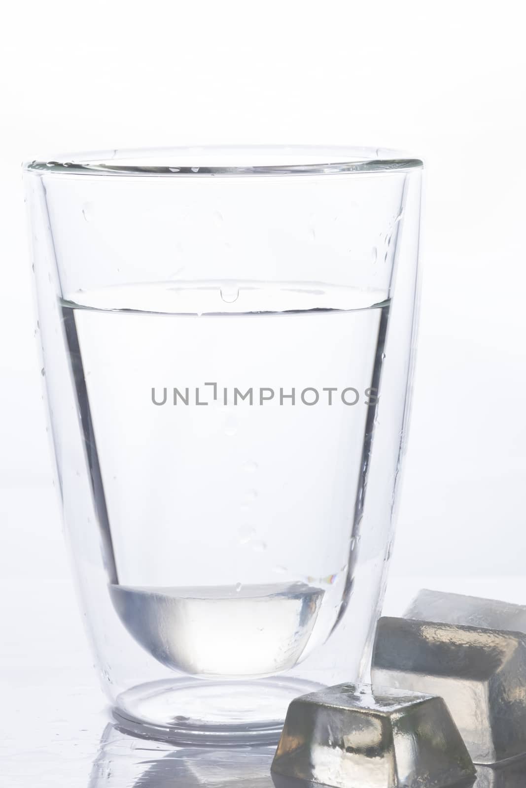 glass of drinking water and ice in front of its