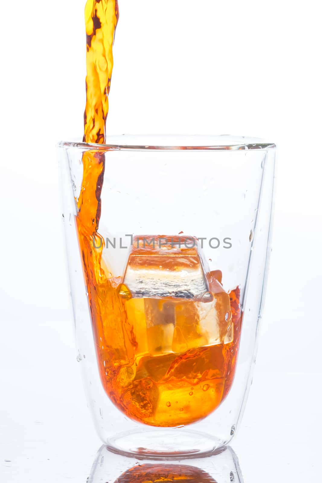 pouring orange water in to clear two layers glass