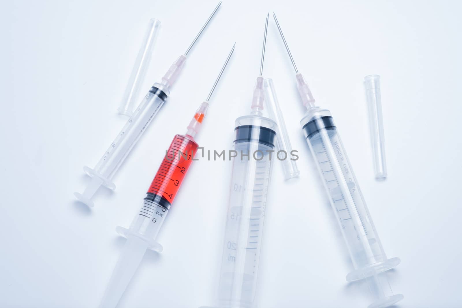 syringes with red vaccine on white background. this photo in cold mood tone.