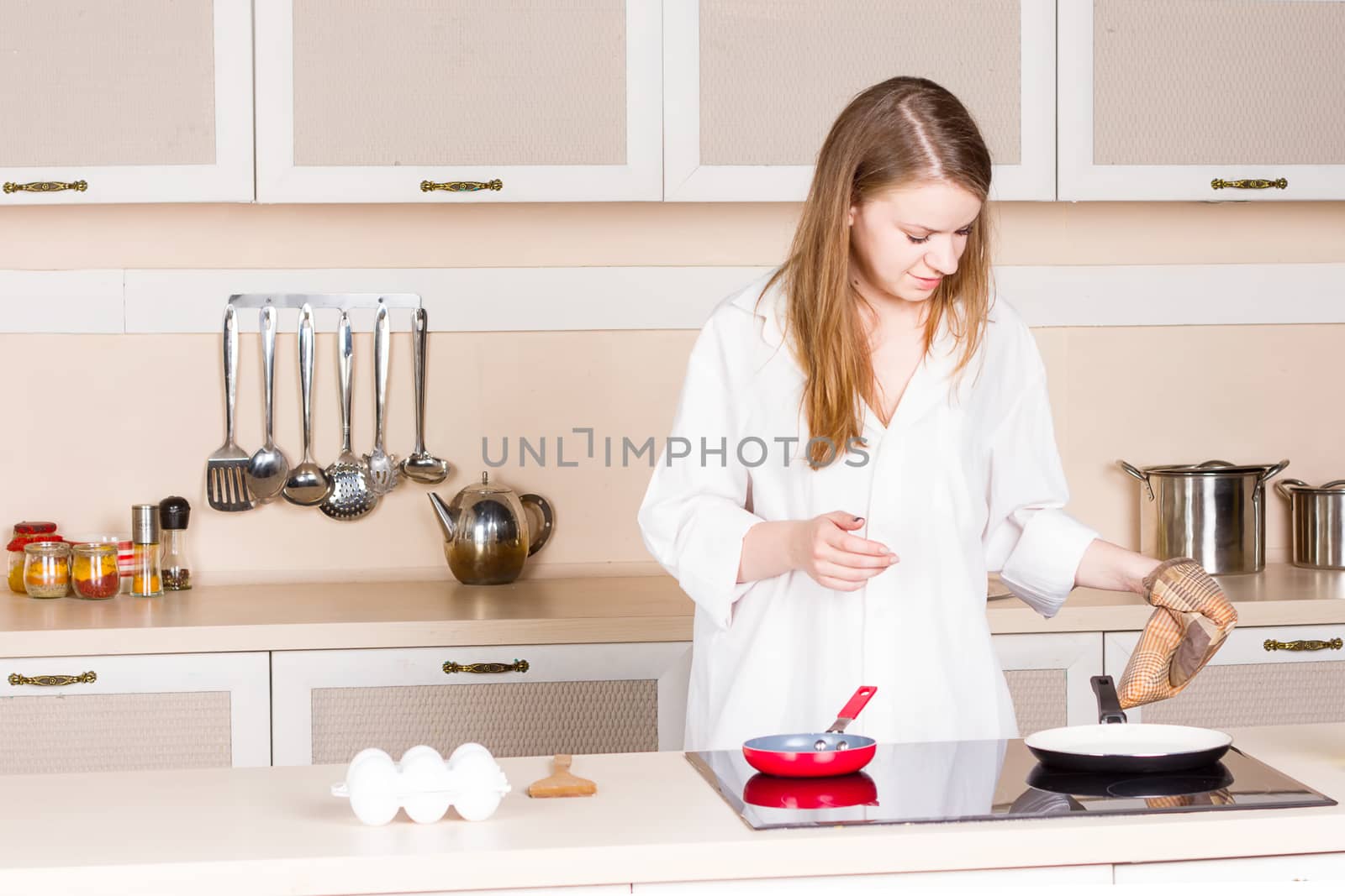 girl in a white men's shirt in the kitchen preparing breakfast