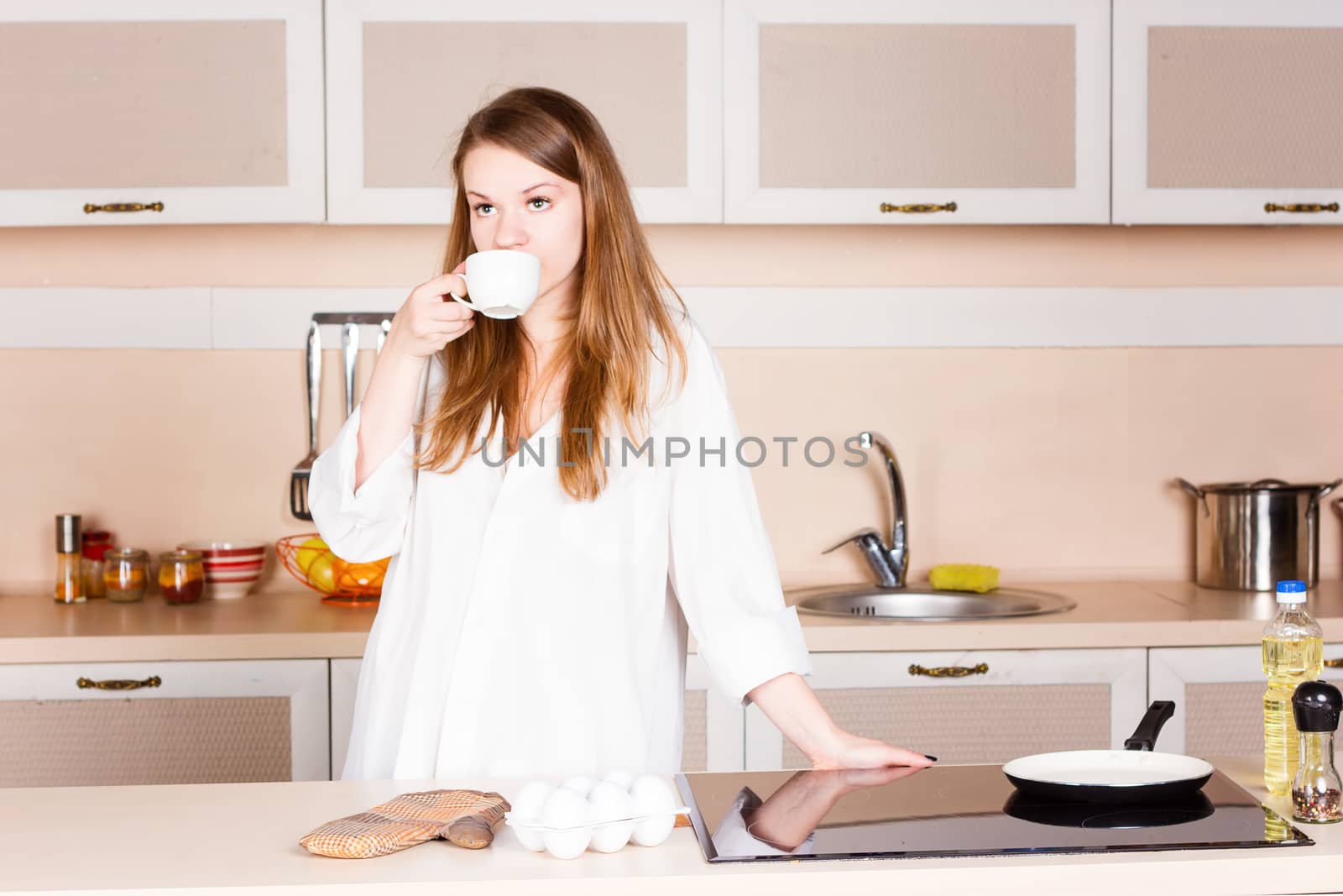 girla white men's shirt with long flowing hair is drinking tea in the kitchen  by victosha