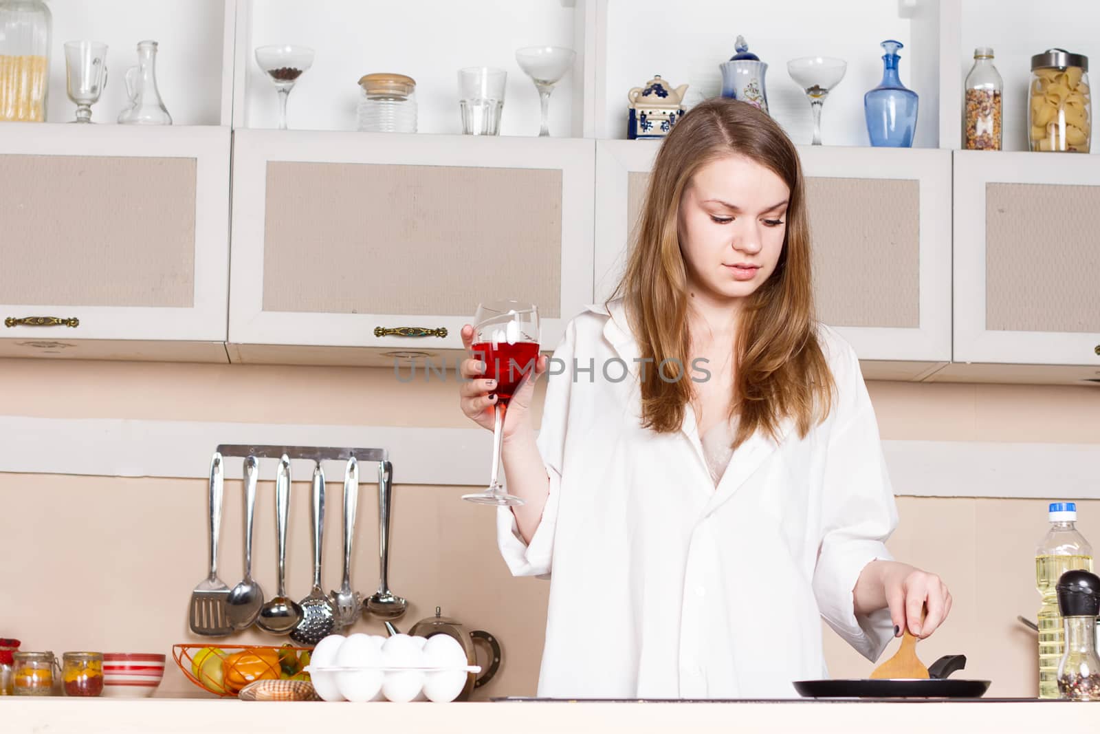 girl in white men's shirt with a glass of red wine near the pans by victosha